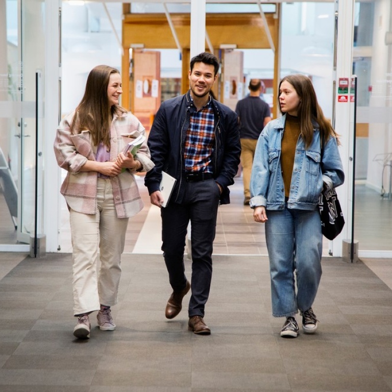 Three students walking in the library.