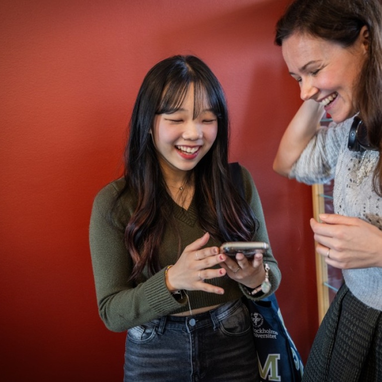 Two happy students looking at a mobile phone.